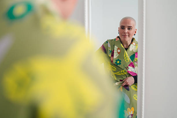 Woman with shaved head reflecting in mirror