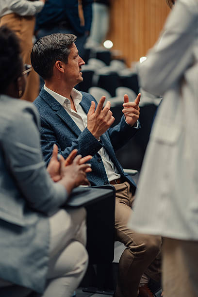 istock Business man conversing actively in conference audience 2247000414