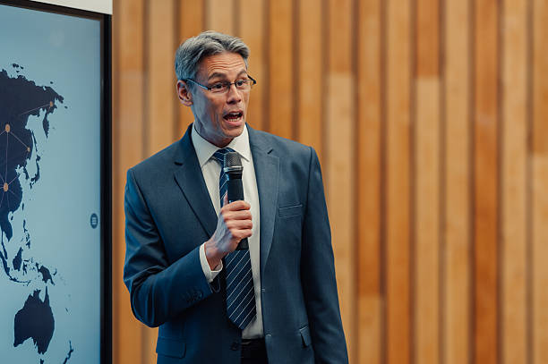 Unrecognizable businessman speaking at a business conference, standing behind lectern