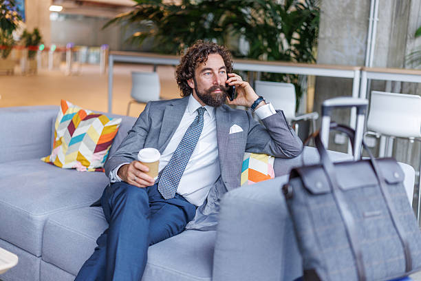 istock Businessman talking on phone while waiting in airport lounge 2247004114