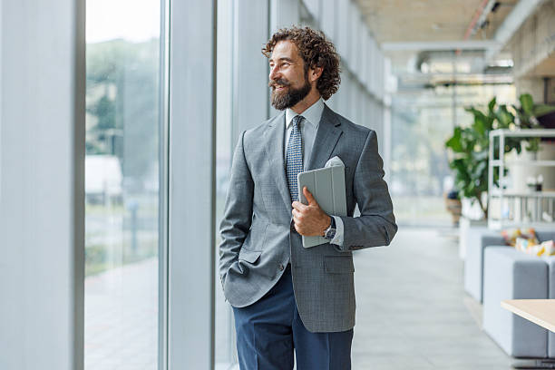 istock Confident businessman looking away standing in modern office 2247004837