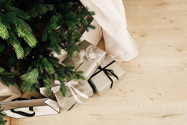 istock Gifts decorated with ribbons sit under a Christmas tree in a cozy home setting 2247009099