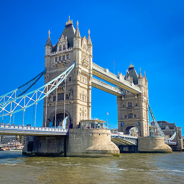 London, uk – july 2025: Tower Bridge captured in bright summer light, viewed from the riverbank, with clear blue skies and calm water in London