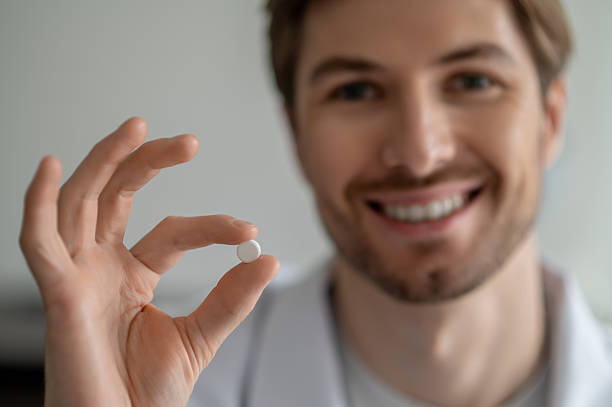 istock Close-up of smiling man's hand holding small white pill 2247011695