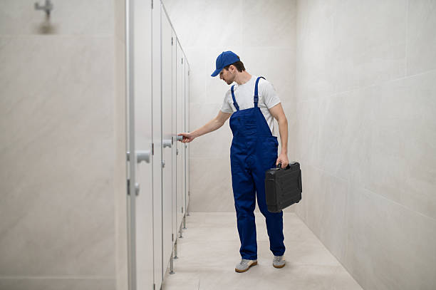 istock Plumber checking toilet cubicle door holding toolbox 2247011807