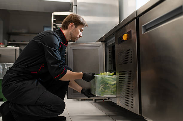 istock Male cook places large container of lettuce placed into refrigerator 2247012082