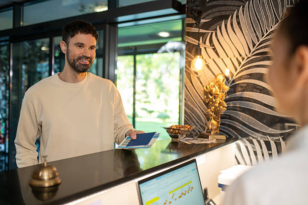 istock Receptionist arranging accommodation of new visitor and taking passport 2247012355
