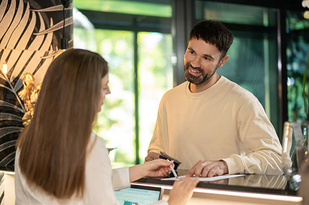 istock Receptionist talking to a male customer and arranging accommodation for him 2247012366