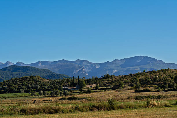 Ainsa rural landscape showing mountains, hills covered with trees and fields under a bright, clear blue sky