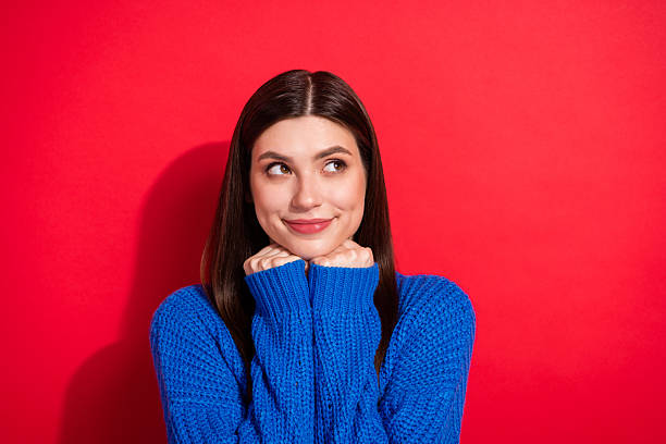 istock Photo portrait brunette in casual pullover touching cheeks smiling looking copyspace curious isolated bright red color background 2247015503