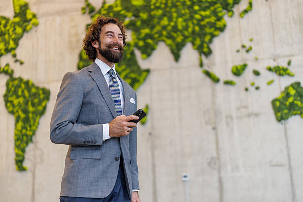 istock Smiling businessman holding phone in front of moss map 2247015539