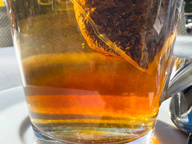 istock Close-up of tea bag steeping in clear glass mug with sunlight reflection 2247021793