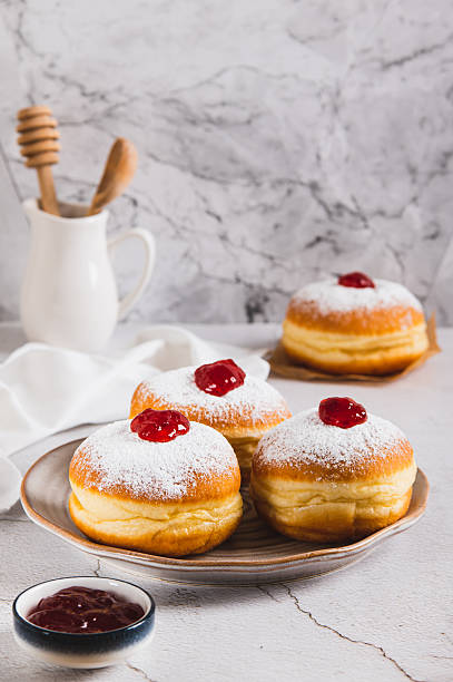 istock Sweet donuts in powdered sugar with jam on a plate on the table vertical view 2247023528