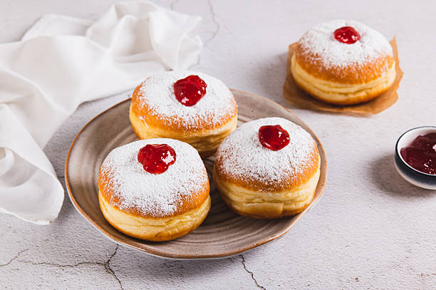 istock Delicious jam filled donuts with powdered sugar on a plate on the table 2247023529