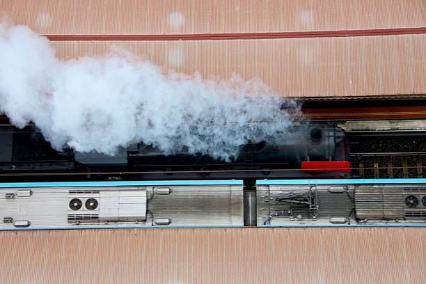 Vintage steam  train on the tracks in Melbourne passing modern passenger train though a train station, viewed from above
