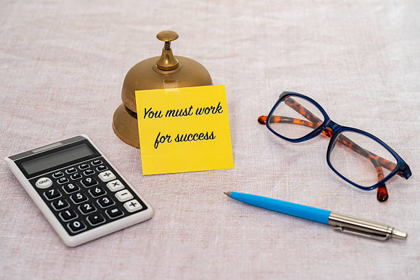 A yellow Post It note with the motivational message You Must Work for Success