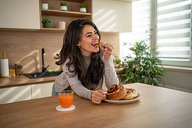 istock Happy woman enjoying cinnamon roll for breakfast 2247025505