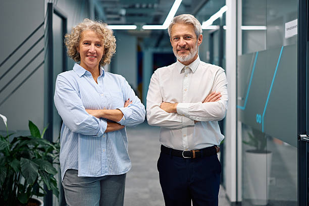 istock Mature business professionals standing with folded arms in office 2247027283