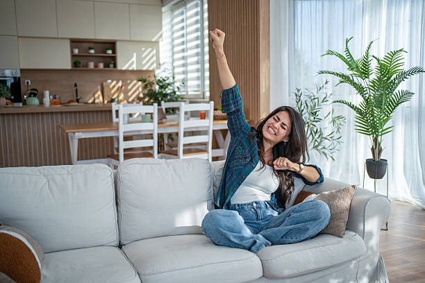 istock Young woman confidently stretching on living room sofa 2247028349