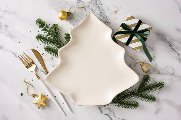 istock A festive table scene featuring a tree shaped plate, gold cutlery, pine sprigs, a striped gift box, and gold ornaments ready for Christmas and New Year celebrations 2247028428