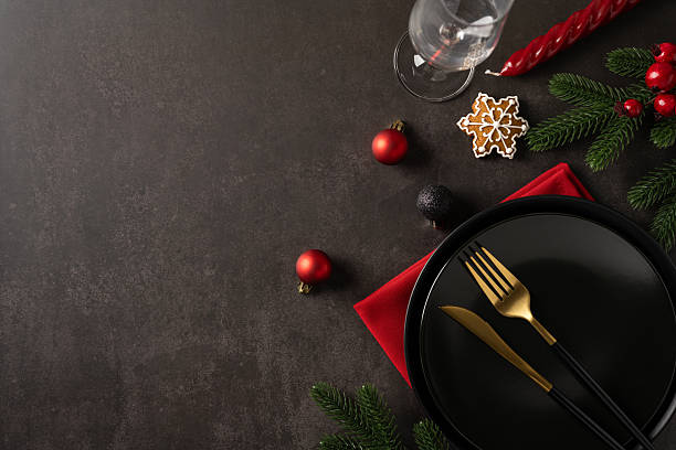 istock A flat lay top view refined holiday table scene featuring a dark plate, gold fork and knife, red napkin, wine glass, gingerbread snowflake and evergreen accents 2247028460