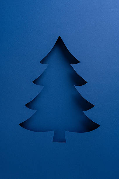 istock Blue vertical card features a dark silhouette Christmas tree cutout on a solid blue background, evoking winter celebration and New Year wishes 2247028483