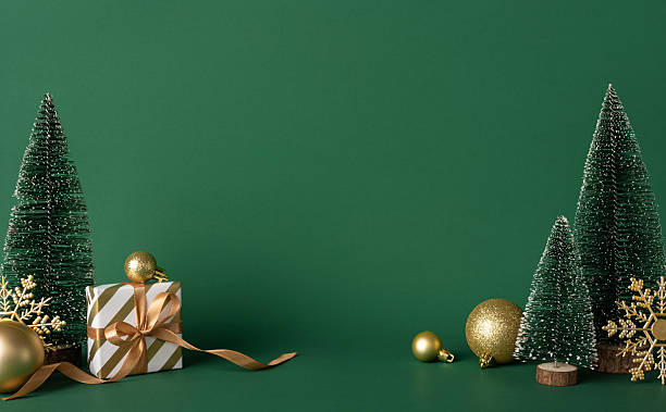 istock A green studio scene featuring a wrapped gift, gold ornaments, and small pine trees, creating a festive holiday atmosphere perfect for Christmas, New Year, and seasonal celebration visuals and greetings 2247028490