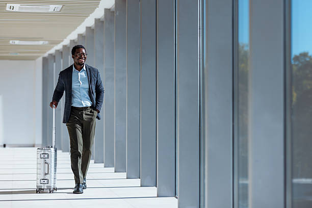 istock Businessman Walking With Rolling Suitcase Through Modern Glass Corridor 2247035516