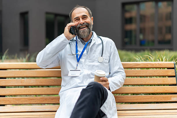 istock Senior doctor smiling having phone call coffee break 2247038929