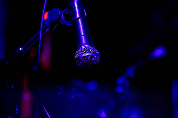 istock Microphone on stage under purple lighting in closeup view 2247039216