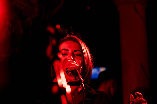 istock Female singer performing on stage in red lighting during night concert 2247039287