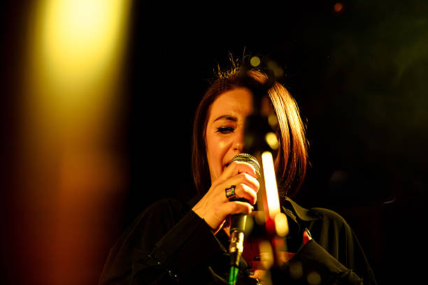 istock Asian female singing on stage with microphone under warm lights 2247039368