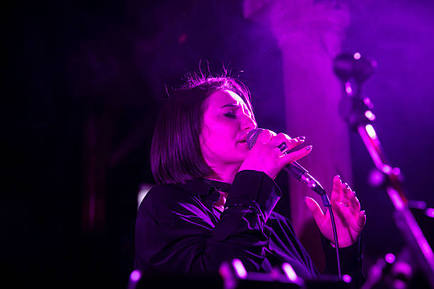 istock Female singer performing live on stage with pink lighting 2247039396