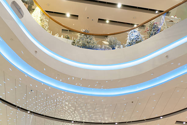 istock Modern atrium with three tiers, bathed in soft natural light, adorned with abstract ceiling pattern, chandeliers, Christmas decorations, transparent glass wall, neutral color palette, contrasting vib 2247041653