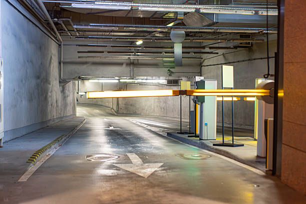 istock An underground parking facility with a concrete ceiling featuring exposed pipes and ductwork, illuminated by recessed artificial lighting casting shadows Signage suggests guidance for vehicle moveme 2247042309