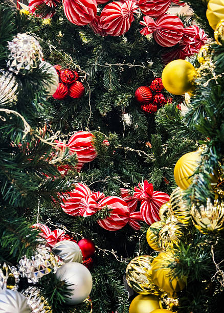 A close-up view of brightly wrapped Christmas gifts placed under a decorated Christmas tree, featuring festive ornaments, candy-shaped decorations, and vibrant holiday colors.
