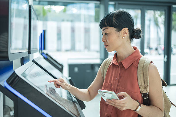 istock Young woman using touch screen information kiosk in modern building 2247045791