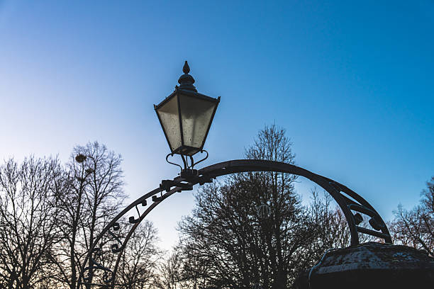 Ornate iron arch with an old lamppost against a clear blue sky