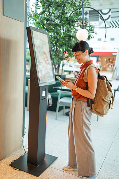 istock Customer using self ordering kiosk in modern food court 2247050220