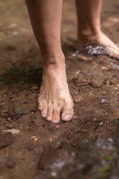 istock Female feet stepping on wet river stones 2247051837