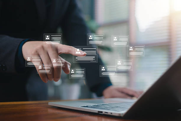 istock Businessman interacting with floating virtual profile cards above a laptop, representing digital HR systems, recruitment, data management, employee analytics, and modern workforce technology. 2247056783