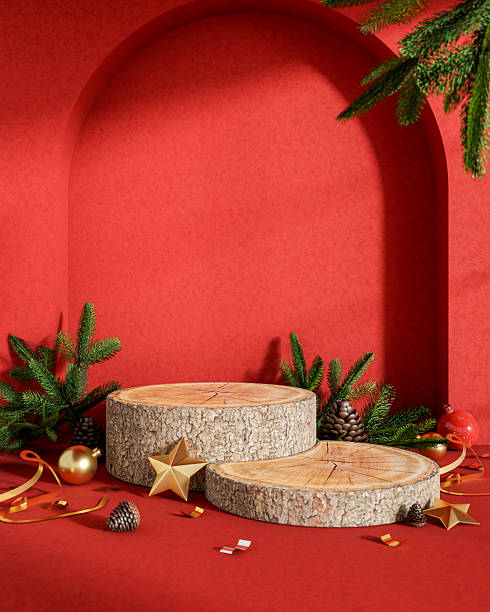 istock Wooden log display platform with Christmas tree pinecone golden ornaments in red archway background. 2247061607