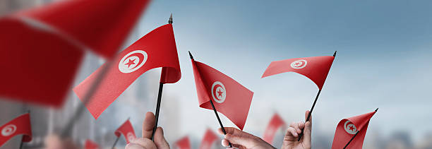 istock Tunisia flags in their hands on a blurred urban background 2247065877
