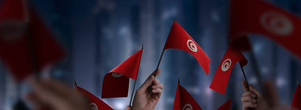 istock Tunisia flags in their hands on a blurred urban background 2247066020