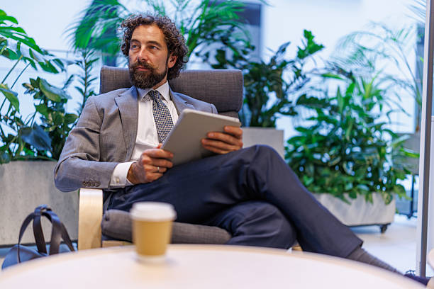 istock Thoughtful businessman holding tablet relaxing in modern office lobby 2247066258