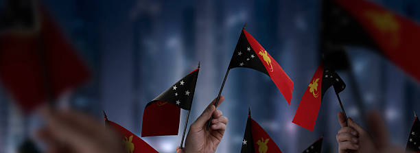 istock Papua New Guinea flags in their hands on a blurred urban background 2247067080