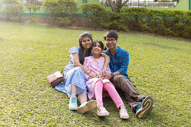 Portrait of smiling mid adult mother dressed in sari standing with cute children against white background