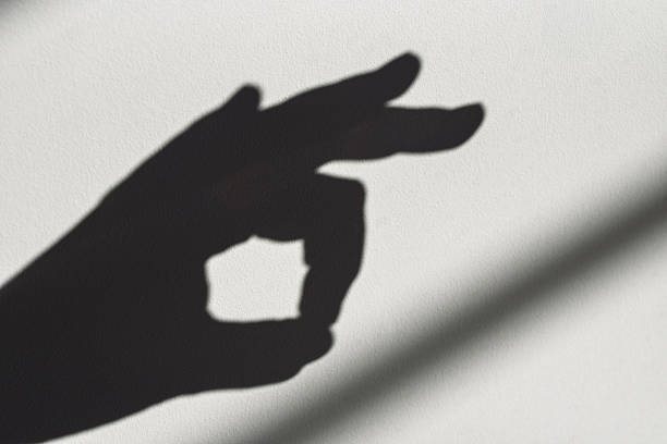 A hand is making a thumbs up gesture in the shade. Concept of positivity and approval