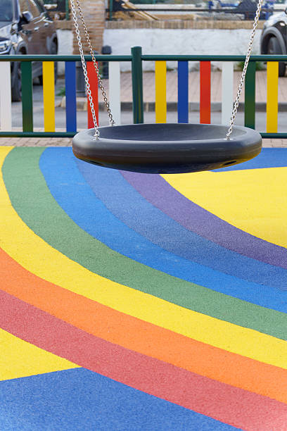 istock Playground swing with vibrant rainbow rubber floor 2247073861