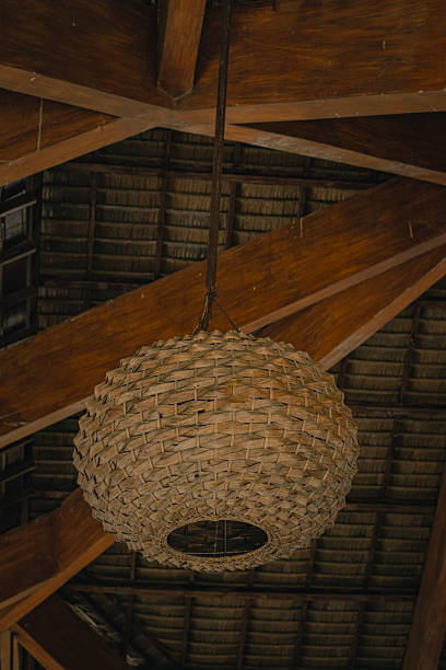 Rattan woven lamp hanging from a wooden ceiling with a rustic ambiance